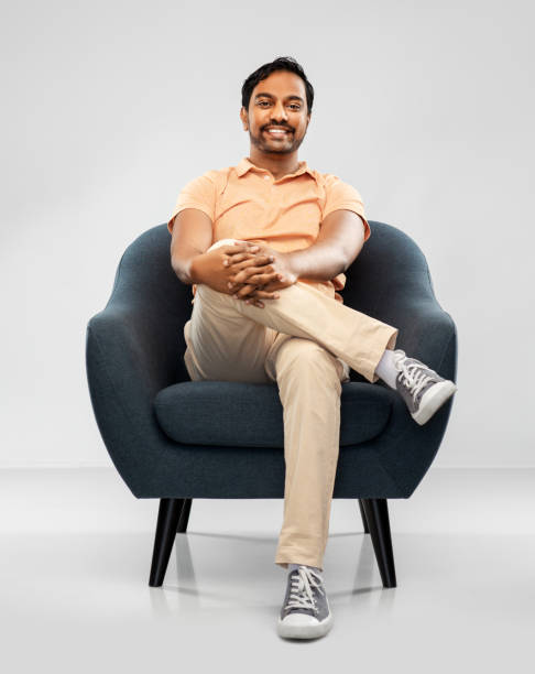 istock happy smiling young indian man sitting in chair 1312146236