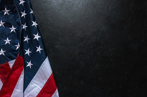 Flag of USA on dark concrete background.\nEmpty space provided for text placement for US celebrations such as: Memorial Day, Independence Day, etc.