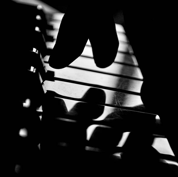 istock Fingers silhouette going to press piano key, black and white 1312146996
