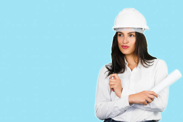 istock A smiling female architect with protective helmet on a light blue background. Ideal shot for renovation, female work, new home and interior makeover. 1312147560