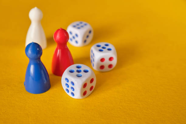 istock Colored game figures chips for board games. Collection of dice cubes on yellow table. 1312149417