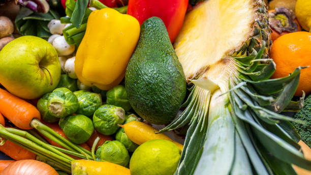 Displayed fresh vegetable and fruit. Halved pineapple, avocado, green pepper, apple, Brussels sprout.