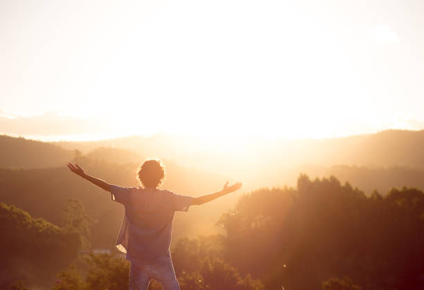 Success and happiness Man with arms raised on top of a mountain with the sunset in the background. Concept of happiness, mental well-being and success. golden hour stock pictures, royalty-free photos & images