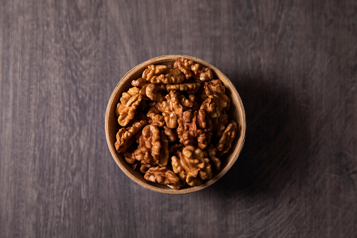 Walnuts in a bowl on brown wooden table