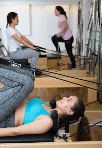 femme exerçant la rotation de torson à la gymnastique utilisant des lits de pilates - pilates machine photos et images de collection