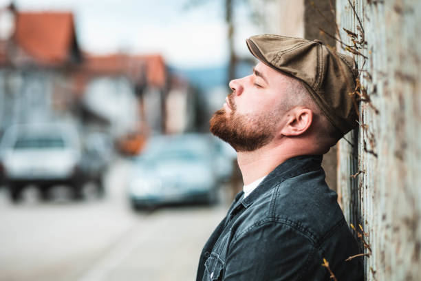 Portrait of a handsome guy with ivy hat leaning on the wall