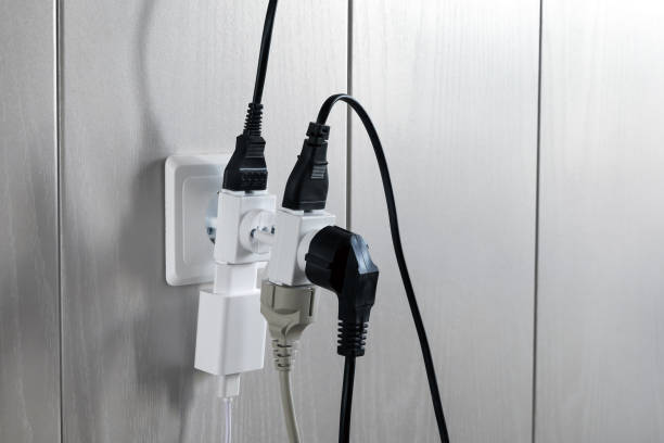 несколько пробок в стене электрической розетки является опасной перегрузки, крупным планом - electric plug outlet network connection plug electricity стоковые фото и изображения