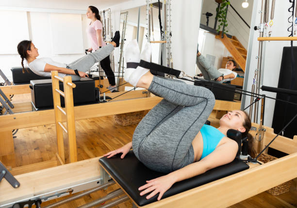 femme exerçant la rotation de torson à la gymnastique utilisant des lits de pilates - pilates machine photos et images de collection