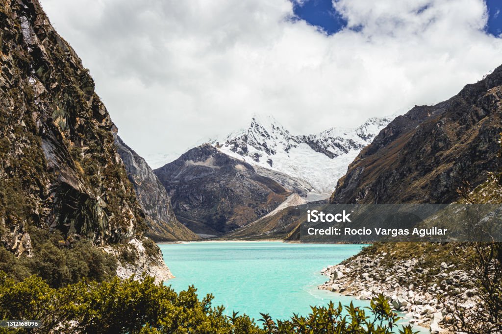 Beautiful Lake Paron with snowy Piramide of Garcilazo in Caraz/Ancash Beautiful view of the Lake Paron with the snow-capped Piramide of Garcilazo, Cordillera blanca, surrounded by mountains, rocks and some trees in Caraz Adventure Stock Photo