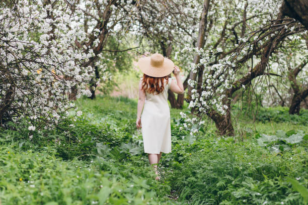 istock Red-haired girl walks in a spring blooming apple orchard 1312170895