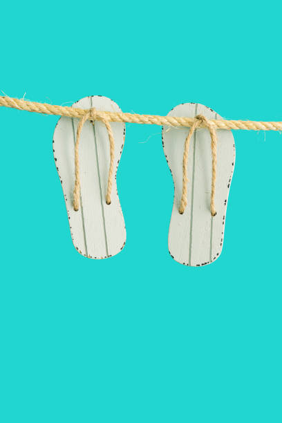 istock Summer concept, grey toy flip-flops hanging on rope. Bright summer minimal style. 1312171518