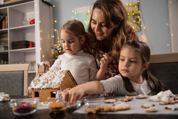istock Mother bonding with her two little daughters while decorating a gingerbread house 1312171668
