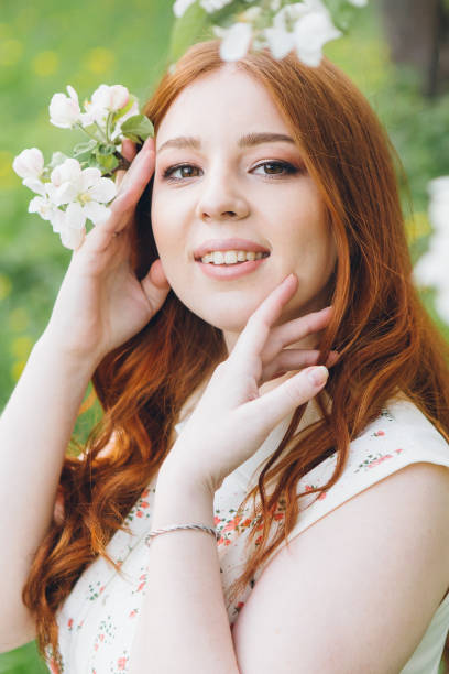 istock Red-haired girl walks in a spring blooming apple orchard 1312172972
