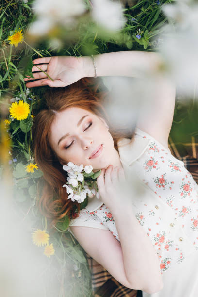 istock Red-haired girl walks in a spring blooming apple orchard 1312173078