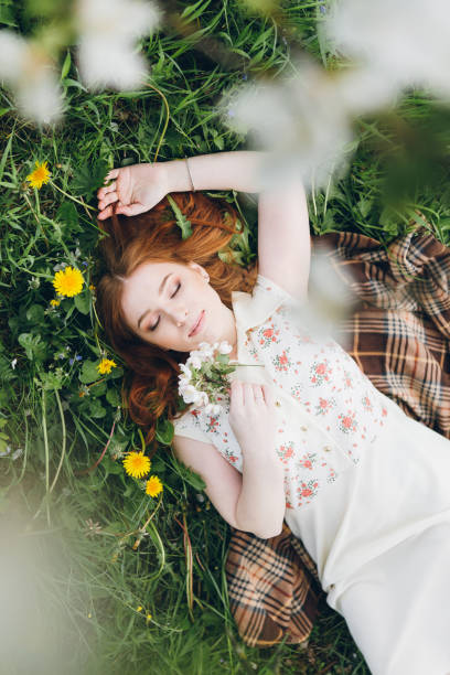 istock Red-haired girl walks in a spring blooming apple orchard 1312173696