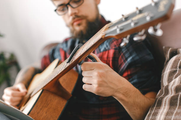 istock Young guitarist hipster at home with guitar fix capo 1312173783