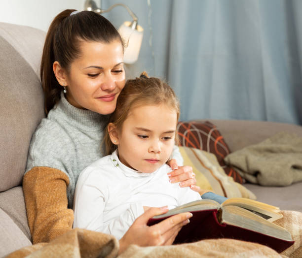 istock Young woman reading an interesting book with daughter 1312174842