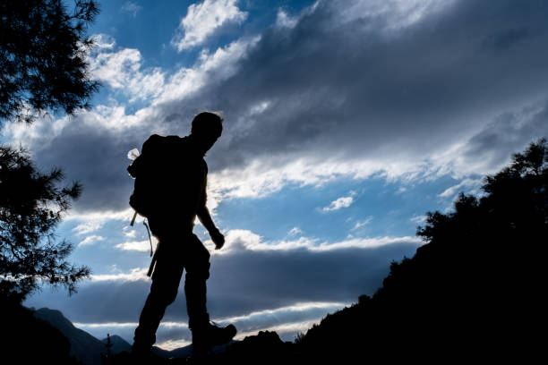 Cloudy landscape. Sunset 60 years old man taking a walk in motion