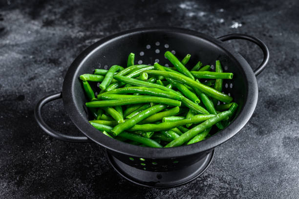 istock Raw green beans in a colander. Black background. top view 1312180945
