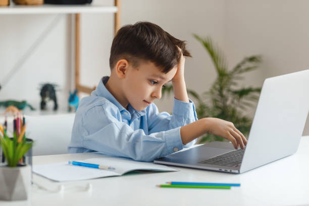 istock Clever kid tired to learn difficult homework using laptop and internet 1312181635