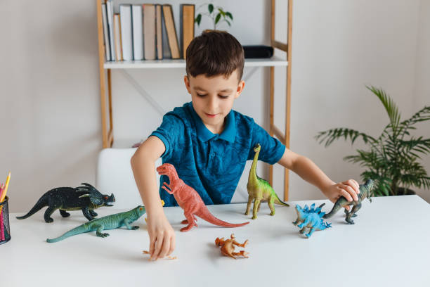 自宅で恐竜と遊んで集中子供。古い学びの少年 - touching children only day europe ストックフォトと画像