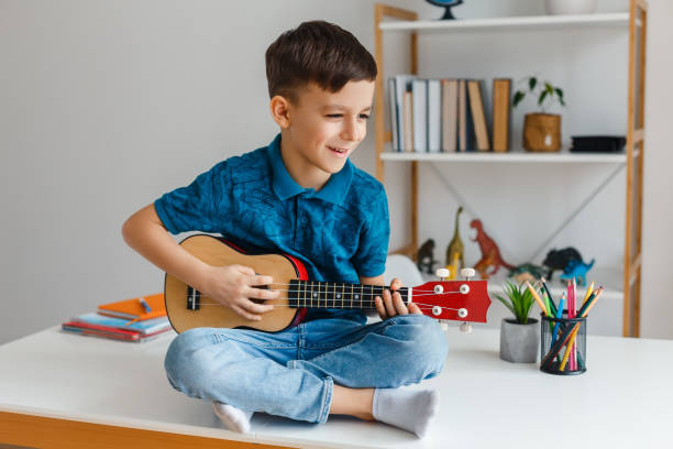 Talented kid playing soprano ukulele sitting on desk