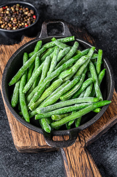 istock Frozen green beans in a pan. Black background. top view 1312181875