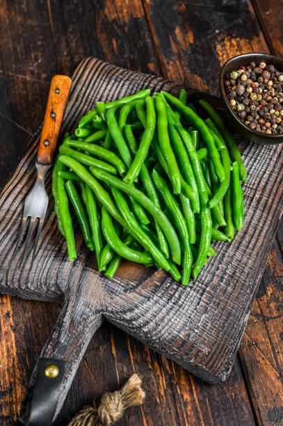 istock Fresh green beans on a cutting board. Dark wooden background. top view 1312182584