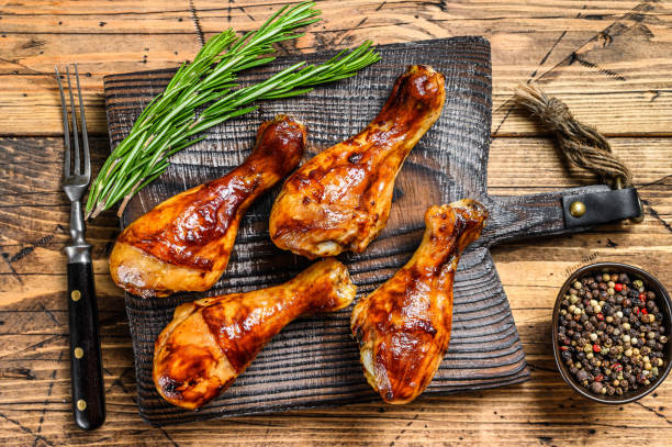 baquetas de pollo asadas a la parrilla en una tabla de cortar de madera. fondo de madera. vista superior - barbecue chicken fotografías e imágenes de stock