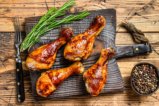 Barbecue roasted chicken drumsticks on a wooden cutting board. wooden background. top view.