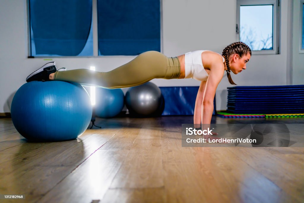 Fit woman workout with fitness ball Young fitness woman workout with fitness ball in push up position at gym Fitness Ball Stock Photo