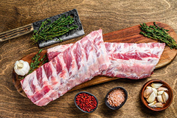 raw pork rack spare ribs with spices, garlic cloves and thyme. wooden background. top view - sparerib imagens e fotografias de stock