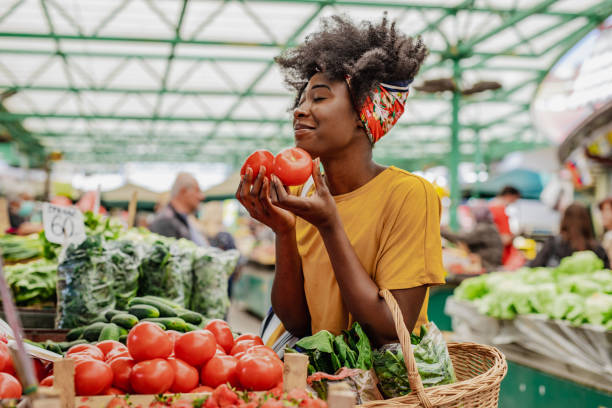 junge afrikanerin kauft tomaten auf dem markt - straßenmarkt stock-fotos und bilder