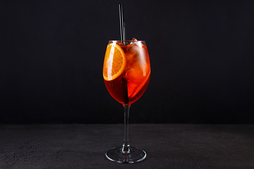 Glass of Spritz cocktail on black background. Summer citrus cold alcohol drink. Classic aperitif