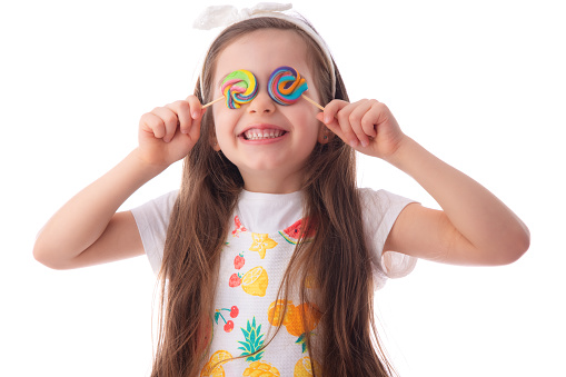 Little kid eating lollipop. Happy beautiful girl with candy isolated on white background.