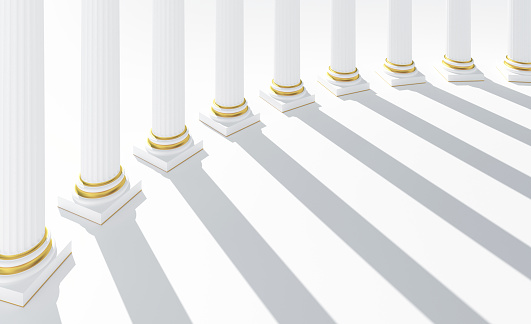 Row of columns forming a colonnade with white marble and golden details. Sunlight casting long shadows. Abstract background of temple or religious building. Copy space. Digital image.