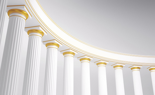 Row of columns forming a curved colonnade with white marble and golden details on capital. Abstract background of temple or place of worship. Copy space. Digital image.