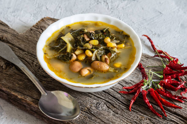 Collard greens soup with corns and kidney beans in white seramic bowl on rustic background Collard greens soup with corns and kidney beans in white seramic bowl on rustic background seramic stock pictures, royalty-free photos & images