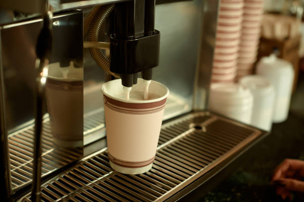 istock automatic coffee maker makes delicious flavored coffee in a paper cup. 1312191890