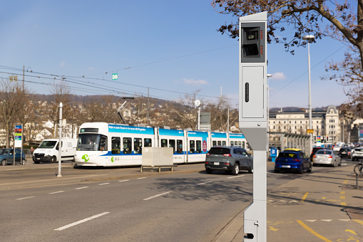 Zurich, Switzerland - March 10, 2021: evening Road traffic: speed and red light radar in one device, white streetcar in background, by day