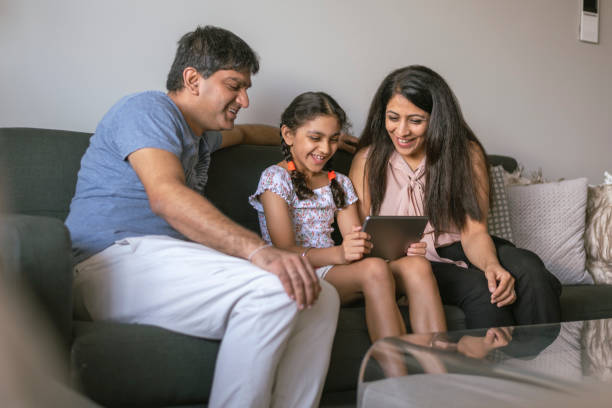 istock Affectionate Indian family using digital tablet together at home 1312205343