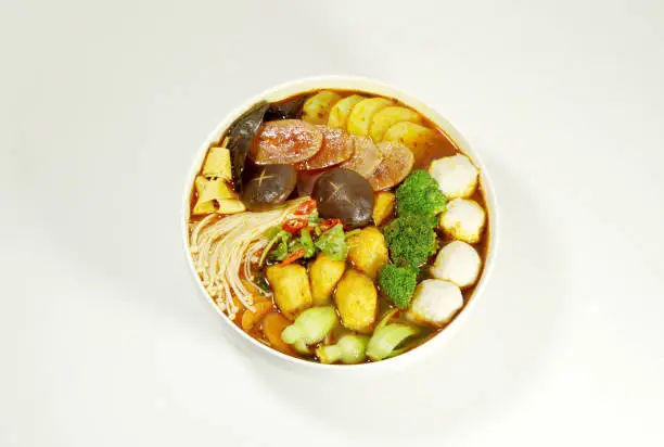 Hot pot is also called Malatang, containing ingredients such as mushrooms, ham and vegetables; white background; top view