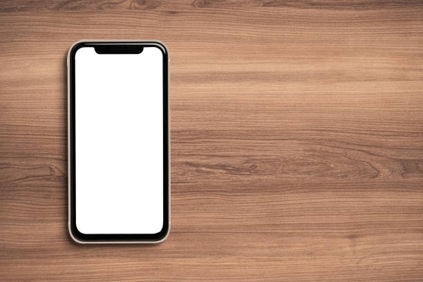 istock Smartphone with white screen for mockup on wooden background. 1312210890