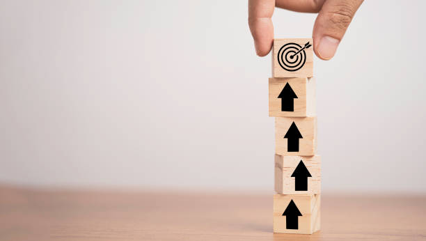 istock Hand putting target board on up arrows which print screen on wooden cube block, increasing and challenge of setup business achievement objective target concept. 1312211479