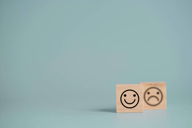 istock Smiley face in front of sadness face which print screen on wooden cube block, emotion selection for customer satisfaction and evaluation concept. 1312212242