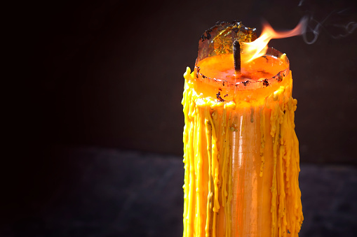 Close up burning candle over black background from Buddhist temple in Bangkok