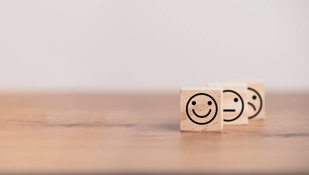 istock Smiley face in front of normal and sadness face which print screen on wooden cube block, emotion selection for customer satisfaction and evaluation concept. 1312212279