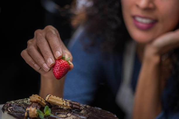 istock Smiling curly-haired female baker decorating round cake with fresh fruits. 1312212329