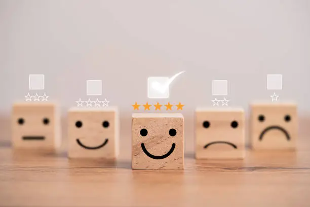 Photo of Customer satisfaction survey concept, human face icons print screen on wooden cube block with stars and mark for evaluate product and service.