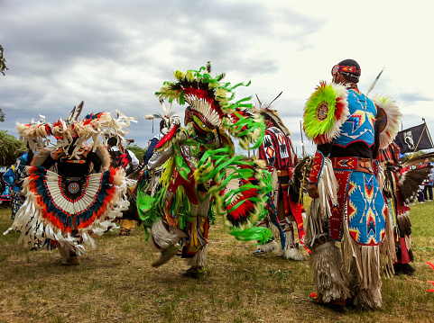 Horizontal closeup of a line of male dancers dressed in ornate, traditional clothing, dancing to the drums at the annual Taos Pow-Wow, New Mexico